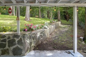 A garden area with a stone wall, wooden pergola, and string lights. - Wooded Retreat w/ Porch & Fire Pit in Stone Ridge (Stone Ridge)