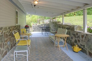 A covered patio area with stone walls, outdoor furniture, and a grill. - Wooded Retreat w/ Porch & Fire Pit in Stone Ridge (Stone Ridge)