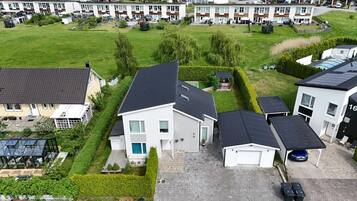 A residential area with detached houses, a green lawn, and a clear sky.