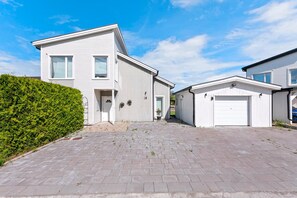 A modern two-story house with a paved driveway and a garage.