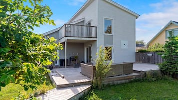 Une maison à deux étages avec un balcon, une terrasse et un petit jardin.