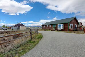 A gravel path leading to a wooden cabin with a green roof, surrounded by a fenced area with a mountain backdrop. - Walkable Fairplay Home w/ Mtn Views! (Fairplay)