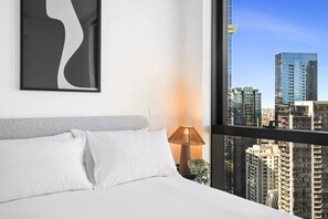 Een hotelkamer met een bed, een lamp en uitzicht op de stad.