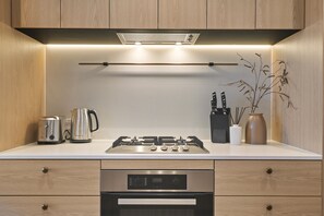 Een moderne keuken met een gasfornuis, broodrooster, waterkoker en een messenblok.