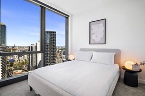 A modern bedroom with a large bed, a city view, and a framed artwork on the wall. - Stylish 2-Bed Apartment Near Crown (Southbank)