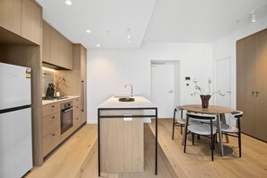 Eine moderne Küche mit Holzschränken, einer zentralen Kücheninsel und einem Essbereich mit rundem Tisch und Stühlen.