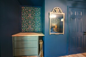 A room with a blue door, a mirror with a decorative frame, and a green cabinet with drawers. - Hocking Hills Area Cabin | Walk to National Forest (Nelsonville)