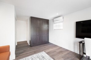 Een moderne woonkamer met een flatscreen televisie, een donker houten kledingkast en een kamerbreed tapijt.