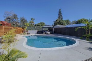 A backyard with a swimming pool, a wooden fence, and a covered seating area. - Private Pool Oasis: Modern 3BR/2BA, Sleeps 8 (San Diego)