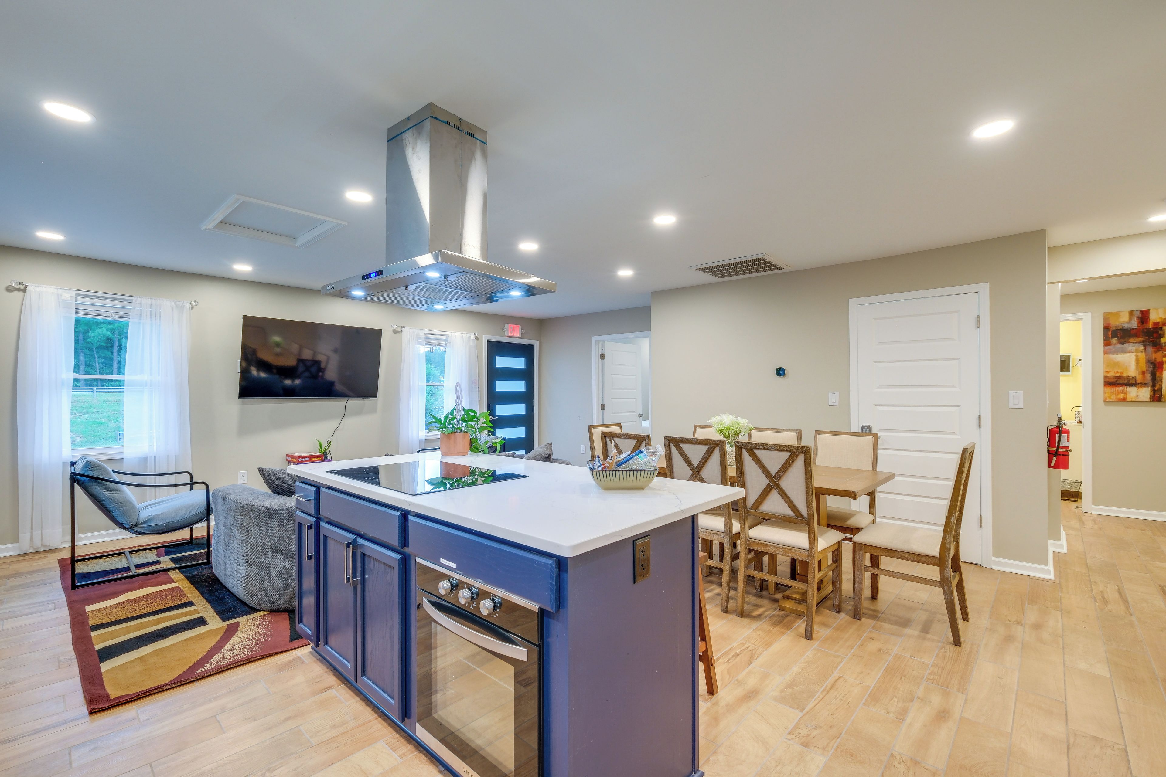 A modern kitchen with a central island, built-in oven, and dining area with wooden chairs.