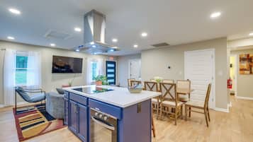 A modern kitchen with a central island, built-in oven, and dining area with wooden chairs.