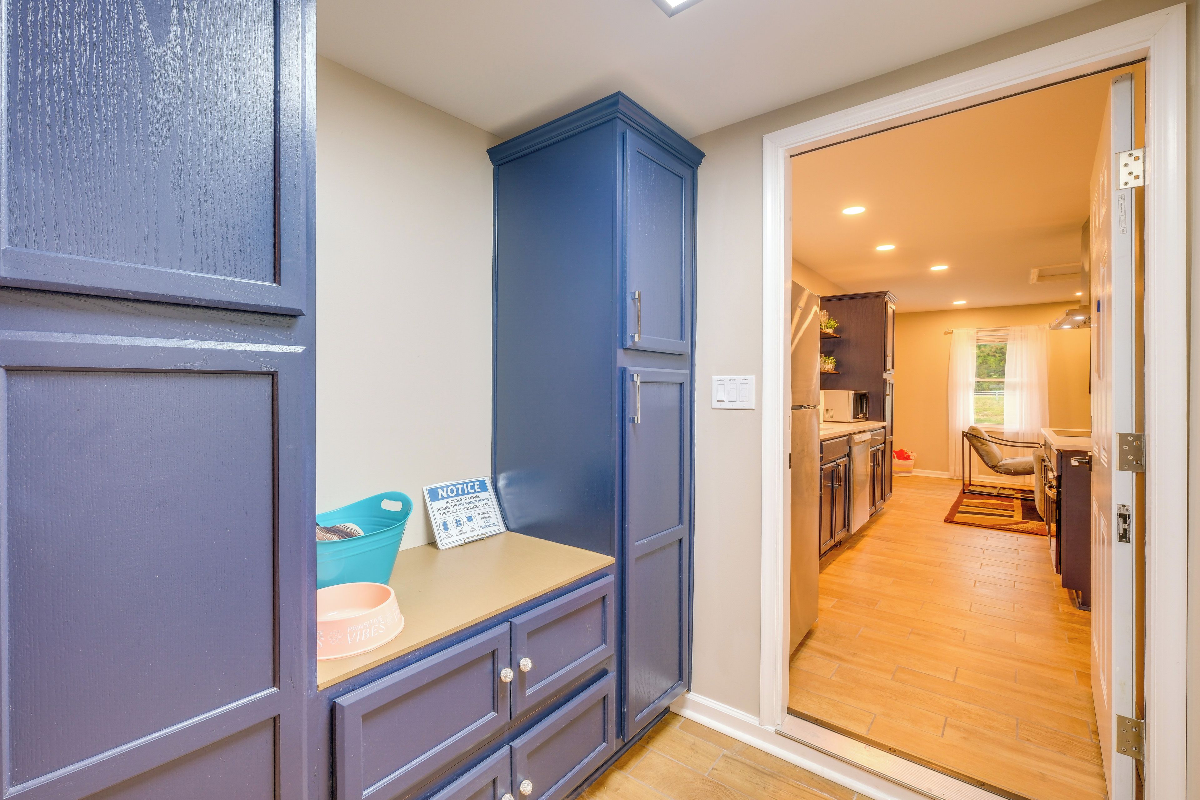 Una cocina moderna con horno empotrado, un área de comedor con mesa y sillas, y un mueble azul con un aviso.