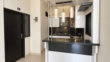 A compact kitchen with a black countertop, stainless steel appliances, and pendant lighting.