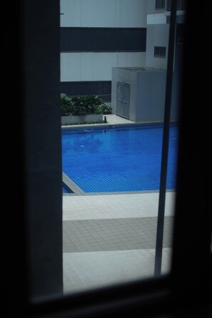 A swimming pool with a tiled edge and a surrounding tiled deck. - Cozy 1-bedroom Suite with Balcony near MOA Pasay City (Pasay City)