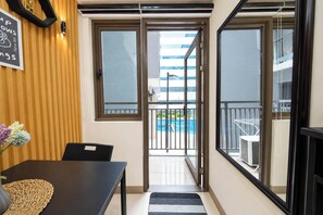Una habitación con puerta de vidrio corredera que da a un balcón con vista a la piscina.