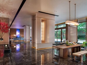 Un moderno vestíbulo de hotel con mostrador de recepción, zona de estar y grandes ventanales con vistas al exterior.