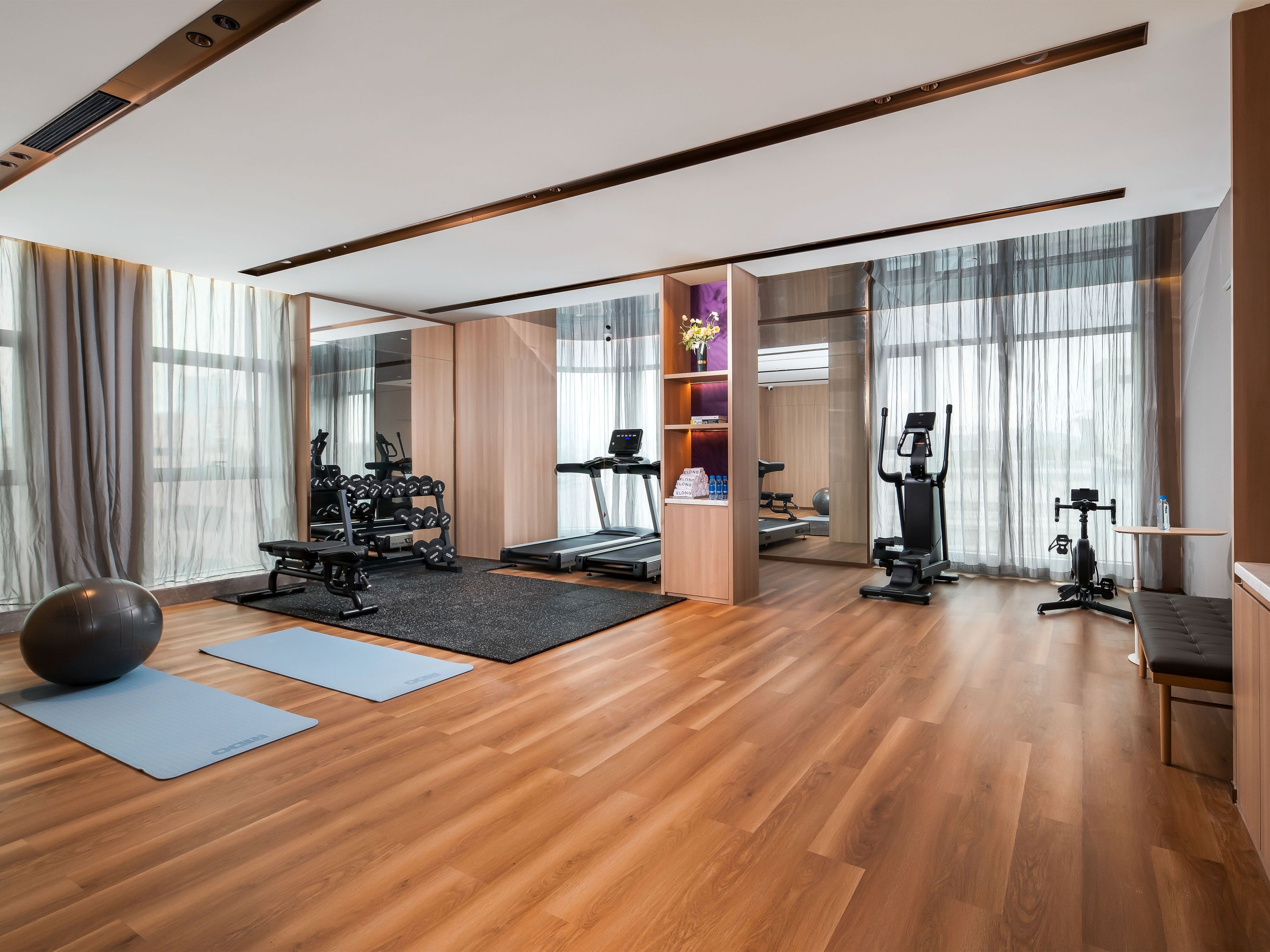 Un gimnasio moderno con equipo de ejercicio, una colchoneta para yoga y una pelota de ejercicios grande.