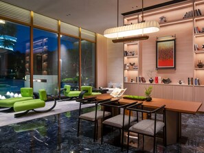 Un interior moderno con comedor, asientos, chimenea y vistas al exterior.
