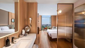 Habitación de hotel moderna con un espejo grande, una tocador con lavamanos y una cama con vistas a la ciudad.