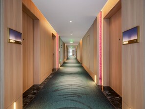 A hotel corridor with a carpeted floor, wooden walls, and illuminated door numbers. - Elong Hotel Shenzhen Pingshan (Shenzhen)