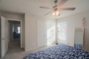 A bedroom with a ceiling fan, a bed with a camouflage-patterned bedspread, a door, and a window with blinds. - 9 Mi to Dtwn! Odessa Home w/ Private Yard (Odessa)