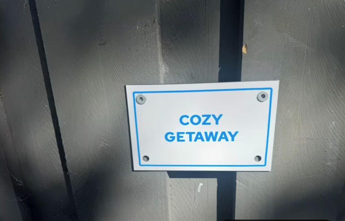 Placa com o texto 'COZY GETAWAY' fixada em uma estrutura metálica.