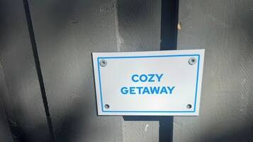 Placa com o texto 'COZY GETAWAY' fixada em uma estrutura metálica.