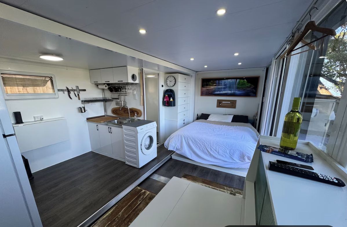 Une chambre compacte comprenant un lit, une fenêtre et une petite kitchenette.