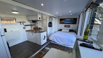 Une chambre compacte comprenant un lit, une fenêtre et une petite kitchenette.