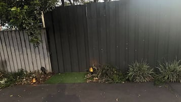 Une clôture en bois, avec une petite portion d’herbe et quelques plantes devant.