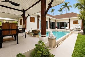 A modern outdoor pool area with a dining setup and lounge chairs. - Stylish 2 Bedrooms Villa with Pool & Tropical Garden (Tambon Rawai)