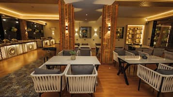 A hotel lobby with a central dining area, seating arrangements, and a bar area with decorative elements.