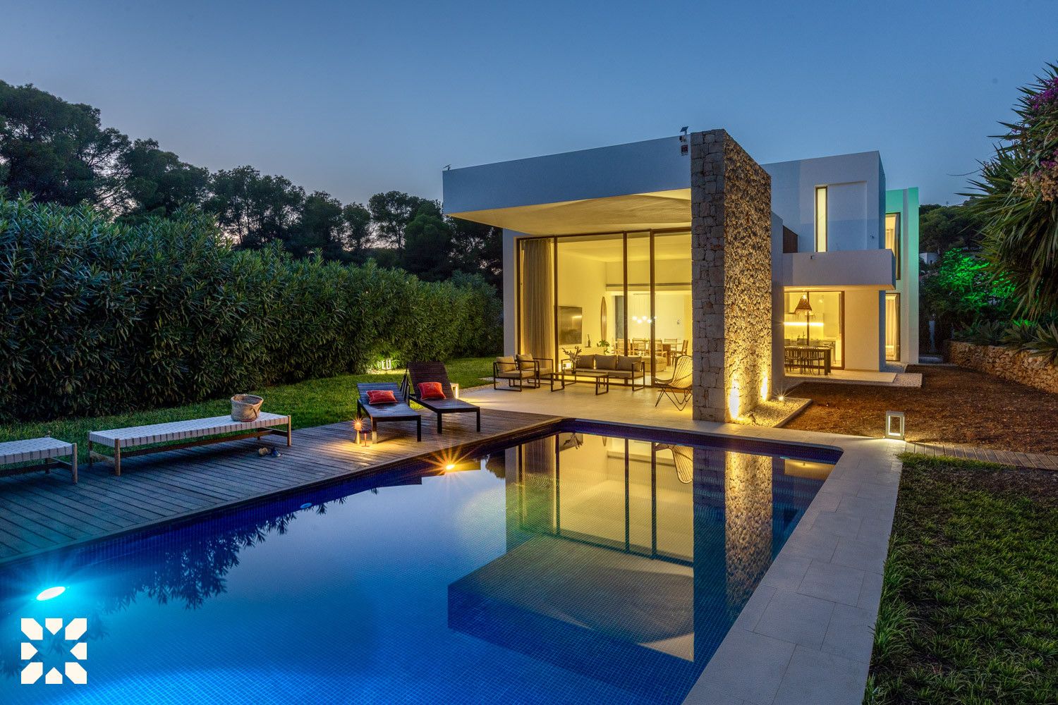 A modern house with a swimming pool, outdoor seating, and a stone pillar.