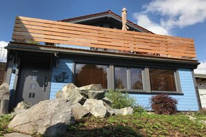 A blue building with a wooden deck, large windows, and a stone wall. - Holiday home in Stiege with barbecue (Stiege)