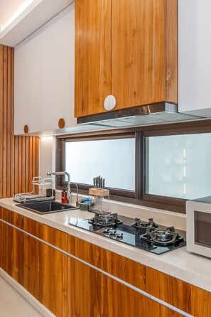 Eine Küche mit Holzausstattung, einer Edelstahl-Spüle und einem Fenster über der Arbeitsfläche.