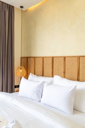 Ein Hotelzimmer mit Bett, Kopfteil, einer Hängelampe und einem Fenster mit Vorhängen.