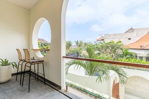 A balcony with a view of a residential area, a round window, and two chairs. - 2BR Batu Bolong Luxury Smart Mediterranean Villa (Kuta Utara)