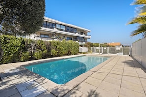 Ein rechteckiger Pool mit einer gefliesten Kante, umgeben von einer gepflasterten Terrasse.