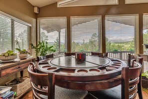 A round dining table with chairs, large windows with blinds, and potted plants. - Walk to Midtown! Mountain-View Ruidoso Retreat (Ruidoso)