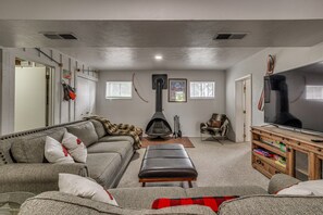 Una sala de estar con sofá, reposapiés, chimenea, televisión y estantería.