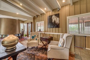 A well-lit living room with a fireplace, comfortable seating, and a large painting on the wall. - Walk to Midtown! Mountain-View Ruidoso Retreat (Ruidoso)