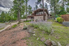 A two-story house with a balcony, surrounded by a forested area and a gravel driveway. - Walk to Midtown! Mountain-View Ruidoso Retreat (Ruidoso)