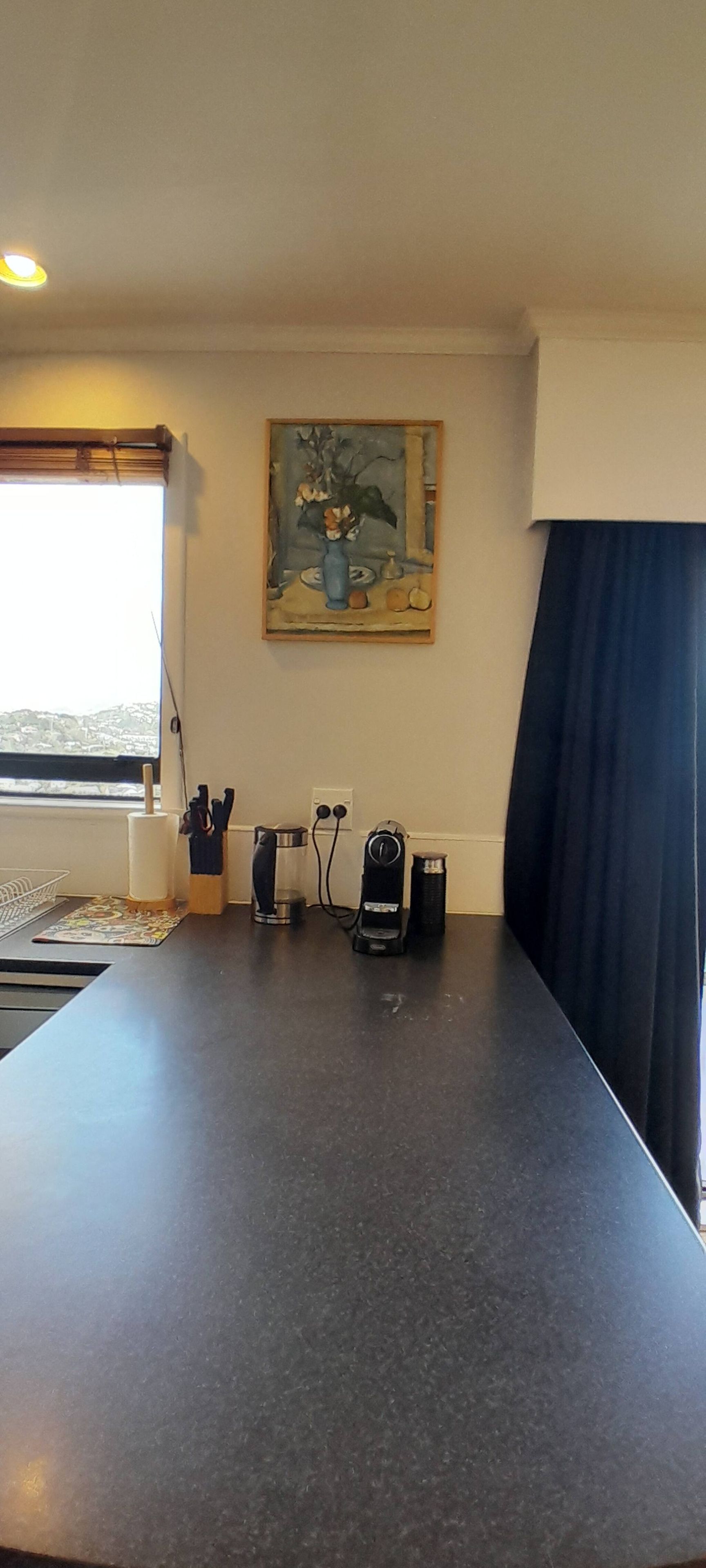 A room with a long table, a painting on the wall, and a window with a view.