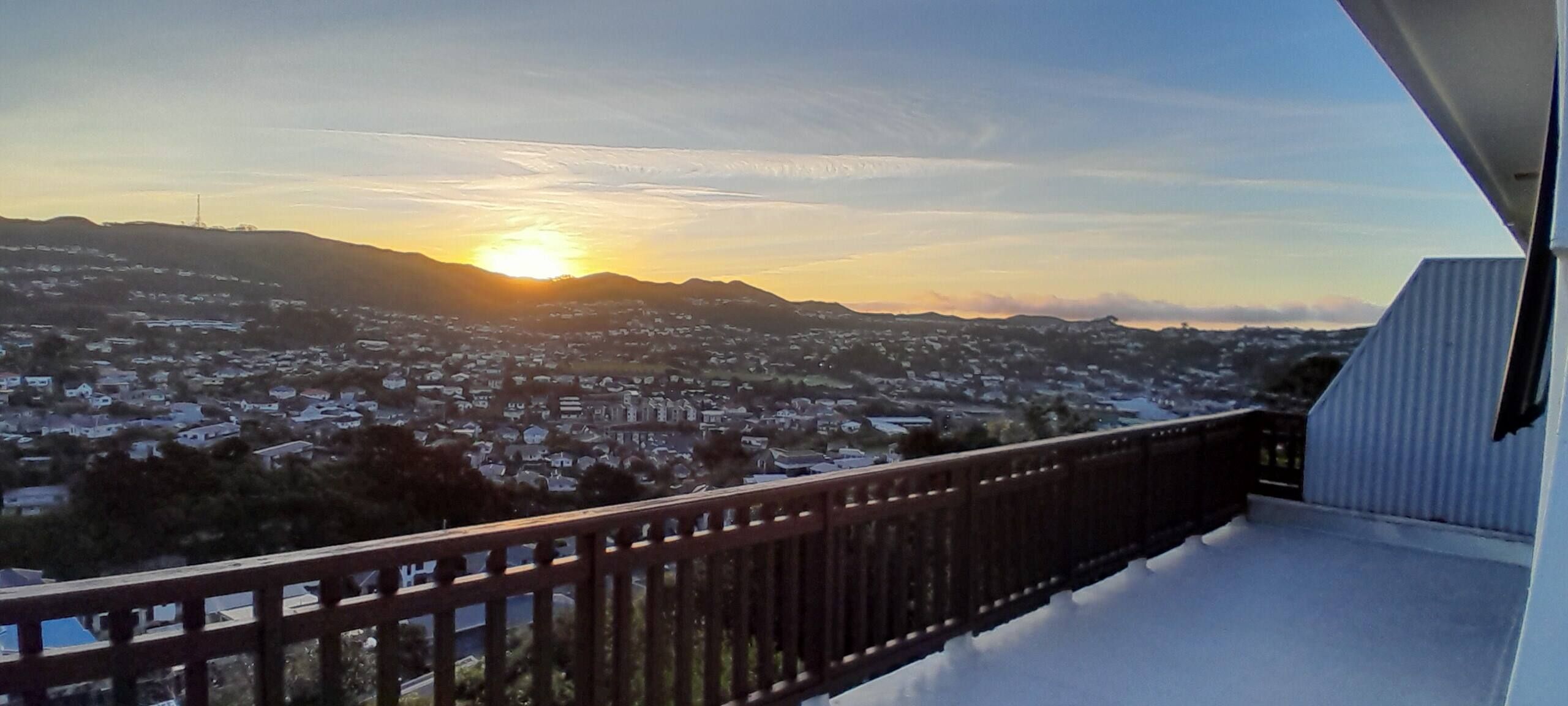 Un balcone con vista su una zona residenziale e un tramonto.