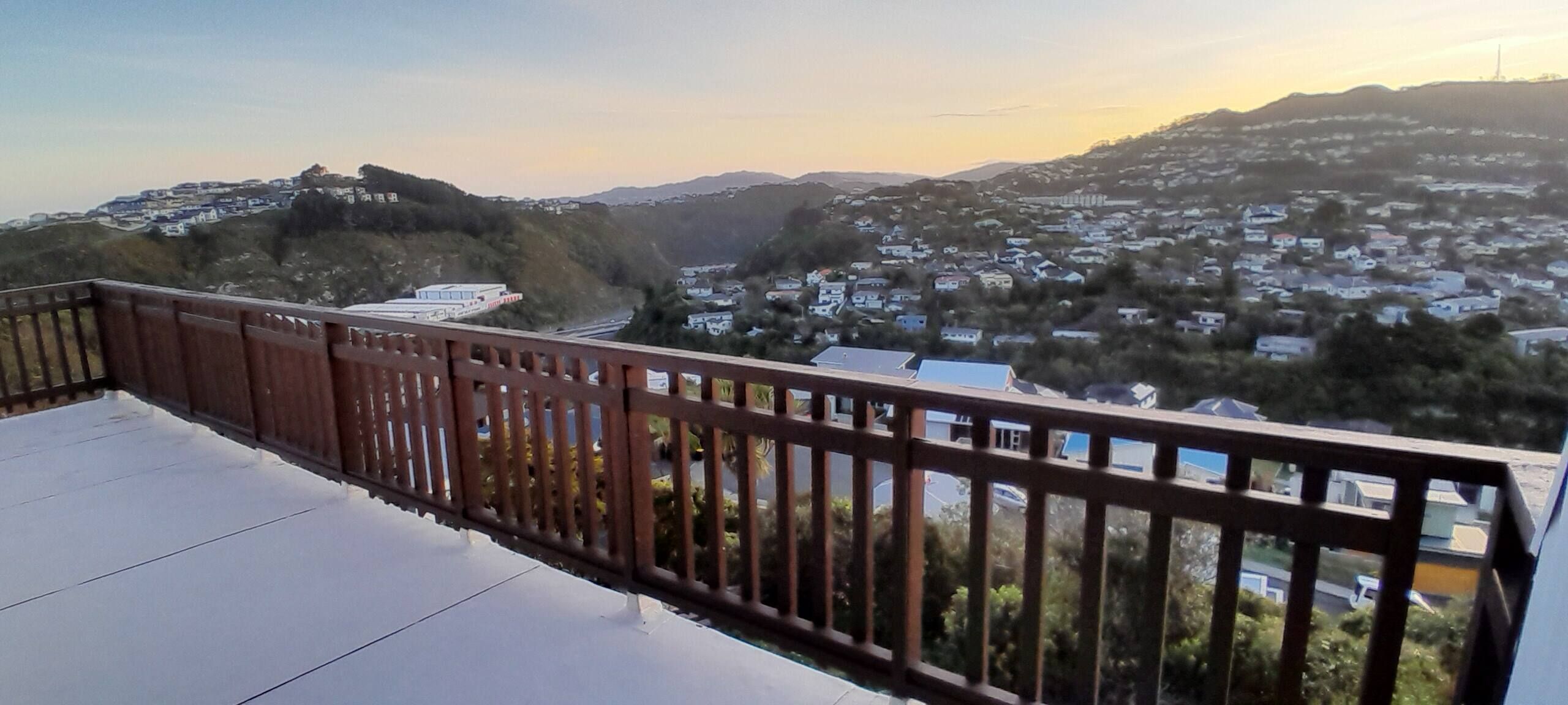 Ein Balkon mit Blick auf ein Wohngebiet und Hügel in der Ferne.