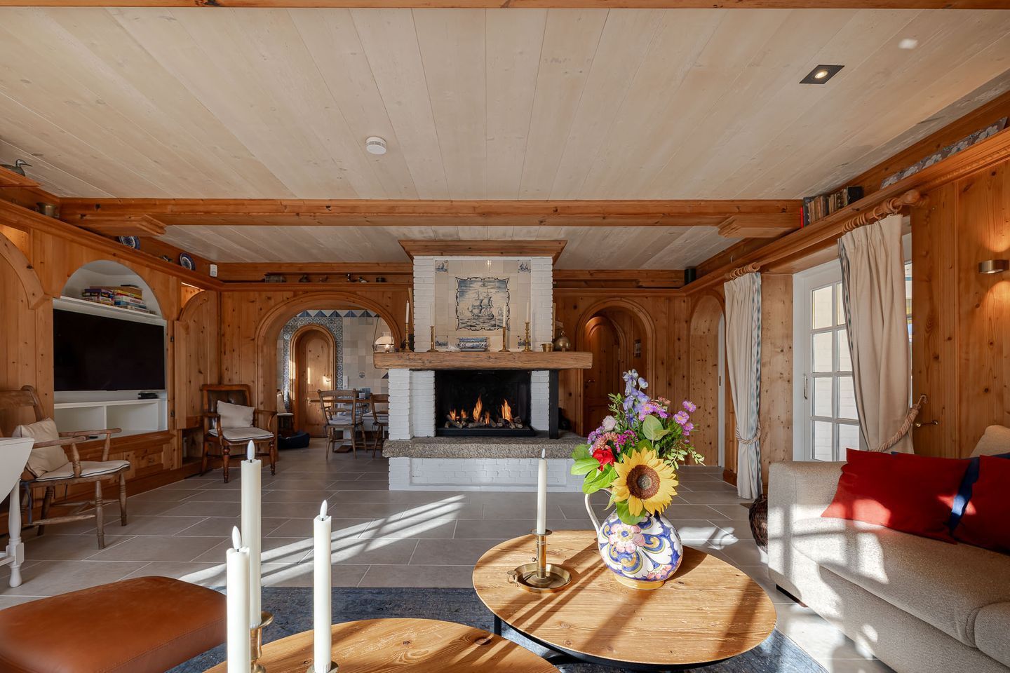 Ein geräumiges Wohnzimmer mit Kamin, Holzmöbeln und einem Fernseher.