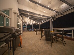Un patio al aire libre con una parrilla, mesas y sillas.