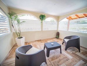 A sunlit room with two wicker chairs, a small table, and potted plants. - Luxury Villa with Pool, Jacuzzi & Beach Access (Sosúa)