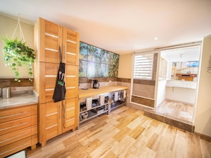 A modern kitchen with wooden cabinets, a built-in oven, and a large window with a tropical view. - Luxury Villa with Pool, Jacuzzi & Beach Access (Sosúa)