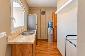 A compact kitchen with a sink, countertop, and a water dispenser. - Central Sosua 1BR , Balcony , Hard Rock Perks (San Felipe de Puerto Plta)